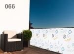 Balkonscherm op maat met geometrisch patroon, donkere fauteuil en groene plant op een zonnig terras.