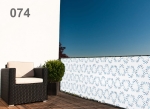 Raster balcony privacy screen with blue pattern shielding a balcony with a modern armchair and a plant.