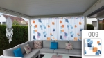 Custom-made net curtain with a colourful geometric pattern on a terrace with a corner sofa and decorative pillows.