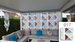 Maßgefertigte Gardine mit geometrischem Dreiecksmuster auf einer Terrasse mit Ecksofa und bunten Kissen.