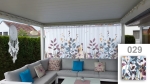 Mitta tilaustyönä tehty verho kuviolla 029 ja kasviaiheella, ripustettuna harmaan puutarhasohvan yläpuolelle terassilla.