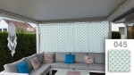 Mittatilaustyönä tehty verho geometrisella kuviolla 045, joka varjostaa terassia, jossa on kulmasohva ja siniset tyynyt.