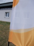 Custom-made advertising sail in white and orange mounted on a hoop in front of an office building.