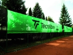 Toprak kort çitine monte edilmiş, Tecnifibre baskılı kişiye özel yeşil tenis kortu brandası.