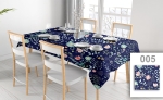 Reclame tafelkleed op maat met blauwe bloemen, uitgespreid over een eettafel met witte stoelen in een licht interieur.