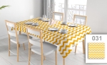 Promotional tablecloth with a yellow zigzag pattern on a rectangular table in a bright dining room with white chairs and tableware.