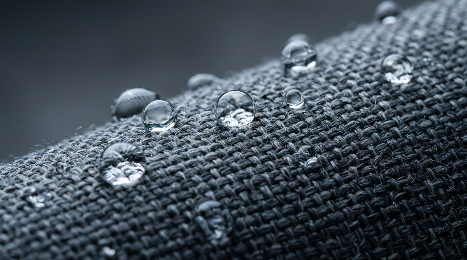 Wassertropfen auf einer dunkelgrauen wasserabweisenden Gewebeoberfläche