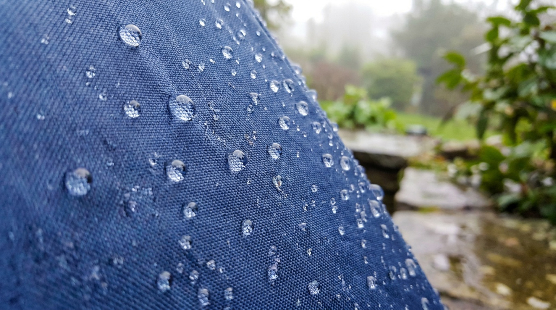 Close-up of water droplets beading on blue waterproof fabric